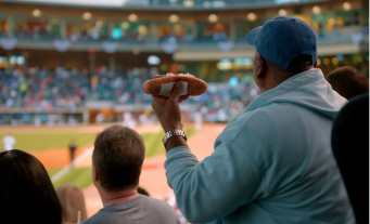 Man holding a hotdog at a baseball game